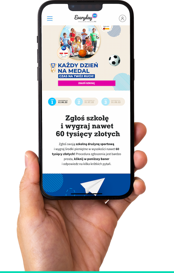 A hand holding a smartphone displaying the polish EverydayMe website with promotional content related with the Biedronka Olympics.