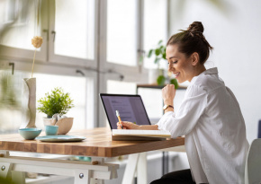 a woman working on a desk with her laptop